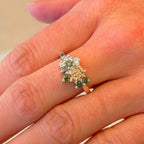 Silverring med orange och gröna moissaniter i elegant handgjord design mot neutral bakgrund.