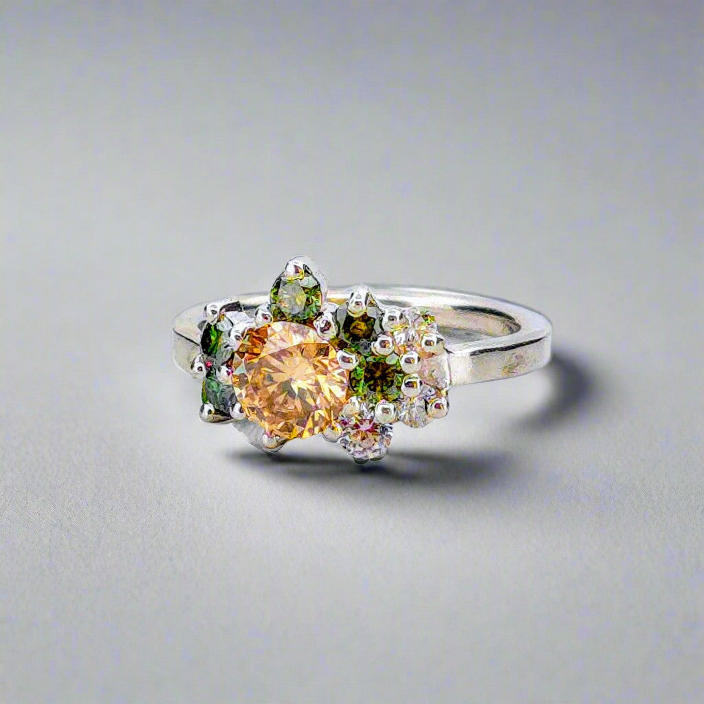 Silverring med orange och gröna moissaniter i elegant handgjord design mot neutral bakgrund.