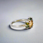 Silverring med orange och gröna moissaniter i elegant handgjord design mot neutral bakgrund.