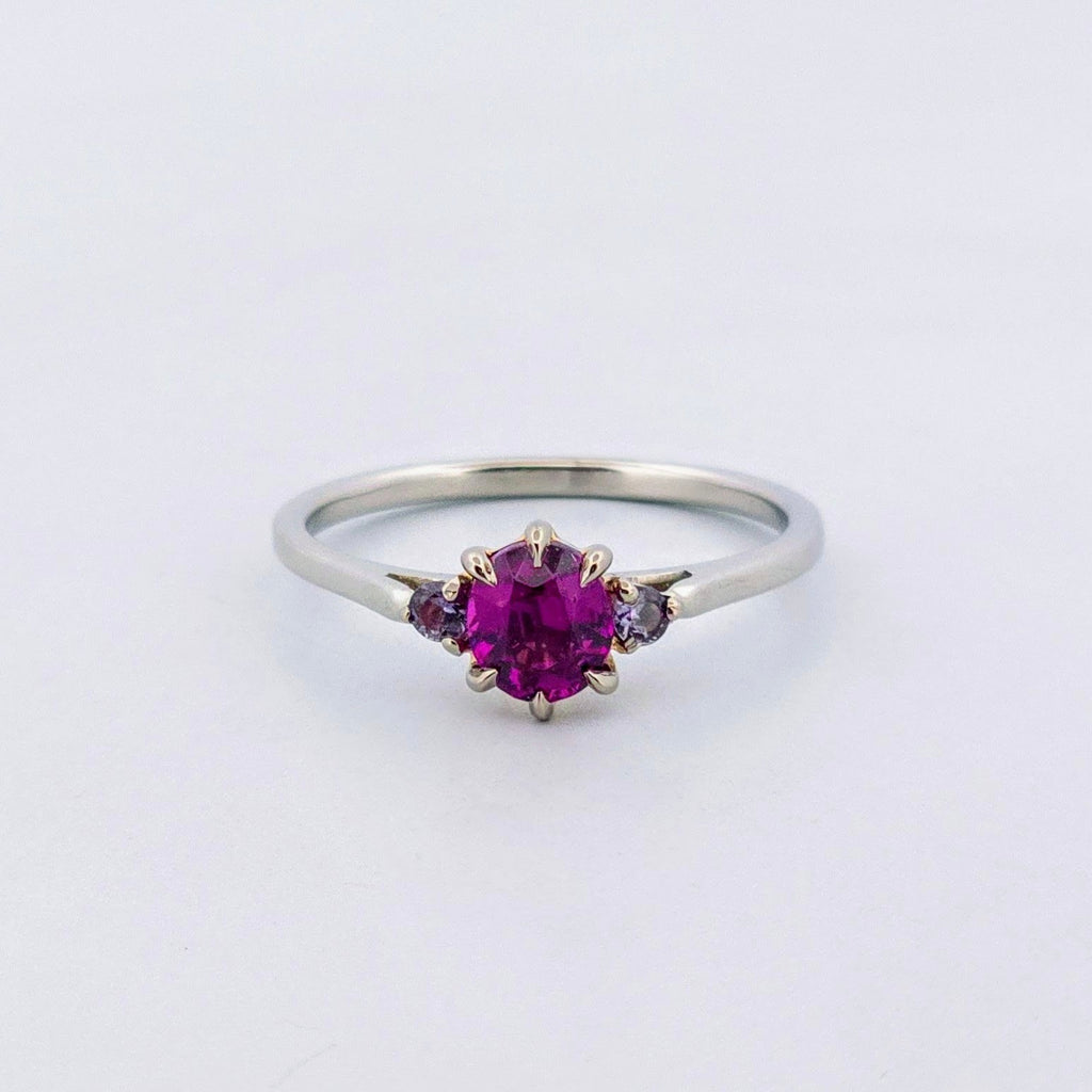 Platina ring med infattning i 18K rödguld, med granat och alexandriter, handgjord lyxdesign mot vit bakgrund.