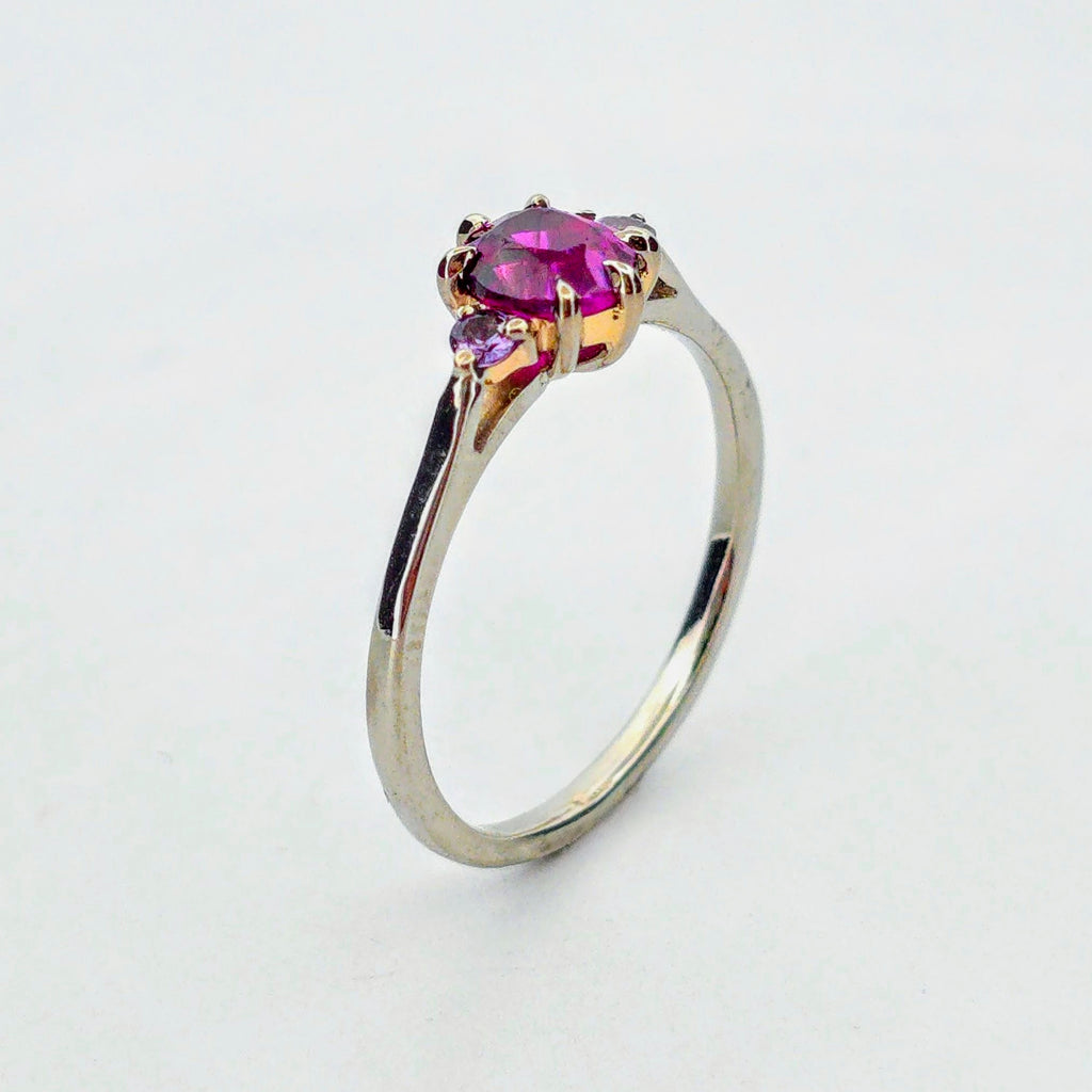 Platina ring med infattning i 18K rödguld, med granat och alexandriter, handgjord lyxdesign mot vit bakgrund.