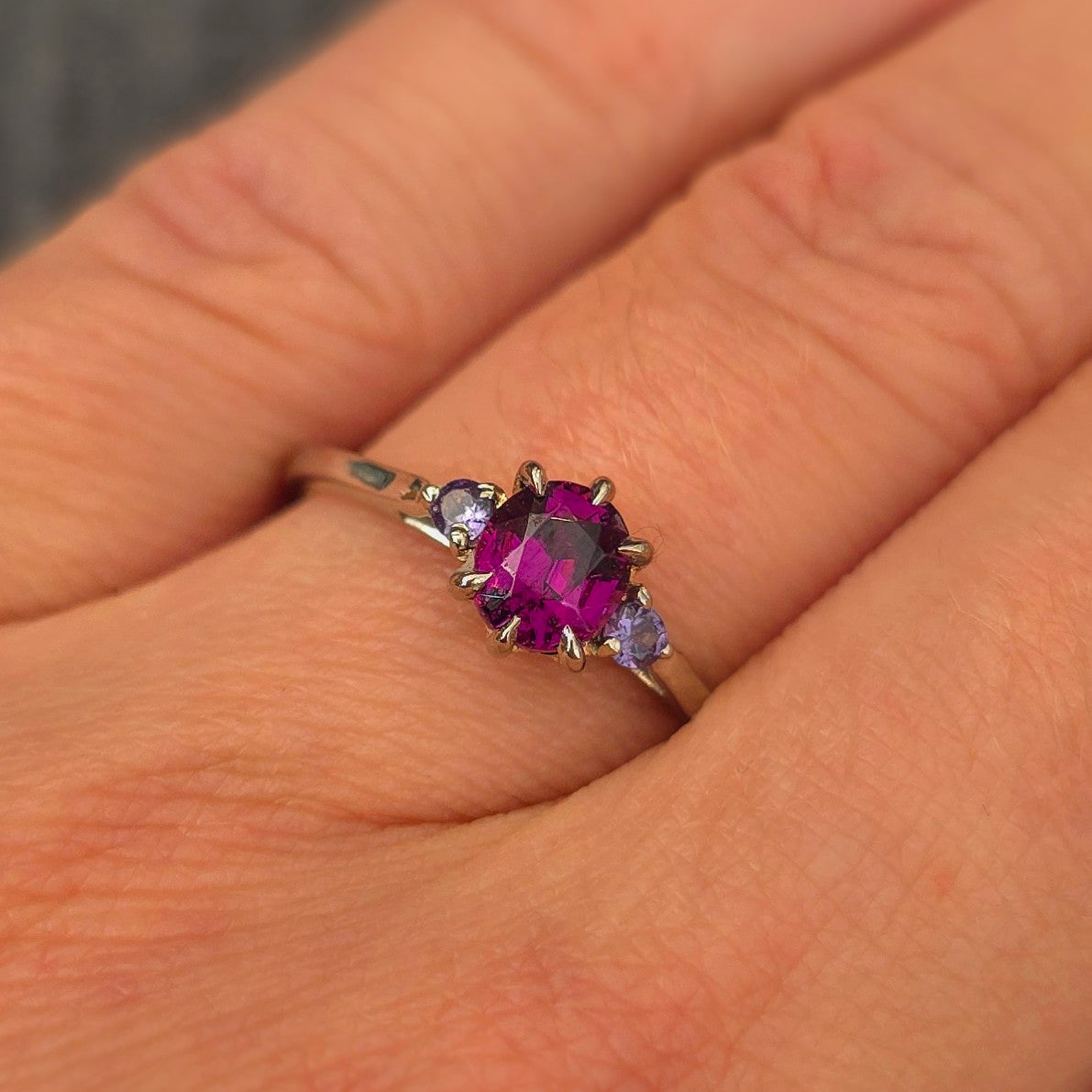 Platina ring med infattning i 18K rödguld, med granat och alexandriter, handgjord lyxdesign mot vit bakgrund.