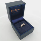 Trendig platinaring med tre gnistrande moissaniter – cushion‑cut mittsten, två trillionslipade sidostenar, och infattning i rödguld