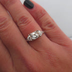 Trendig platinaring med tre gnistrande moissaniter – cushion‑cut mittsten, två trillionslipade sidostenar, och infattning i rödguld