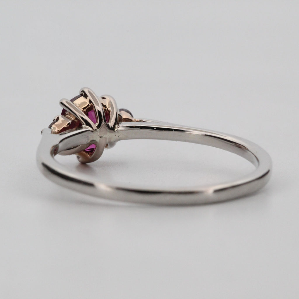 Platina ring med infattning i 18K rödguld, med granat och alexandriter, handgjord lyxdesign mot vit bakgrund.