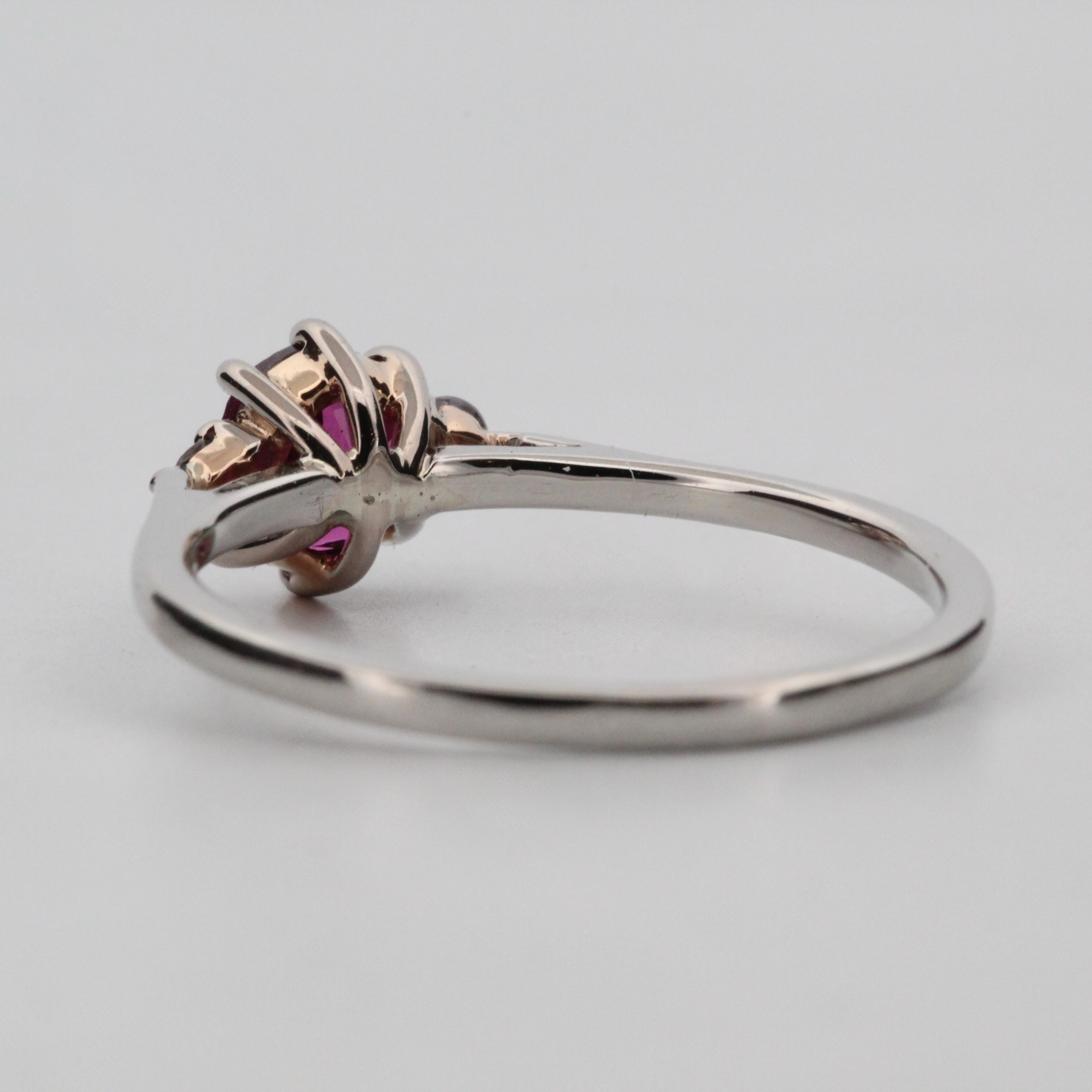 Platina ring med infattning i 18K rödguld, med granat och alexandriter, handgjord lyxdesign mot vit bakgrund.