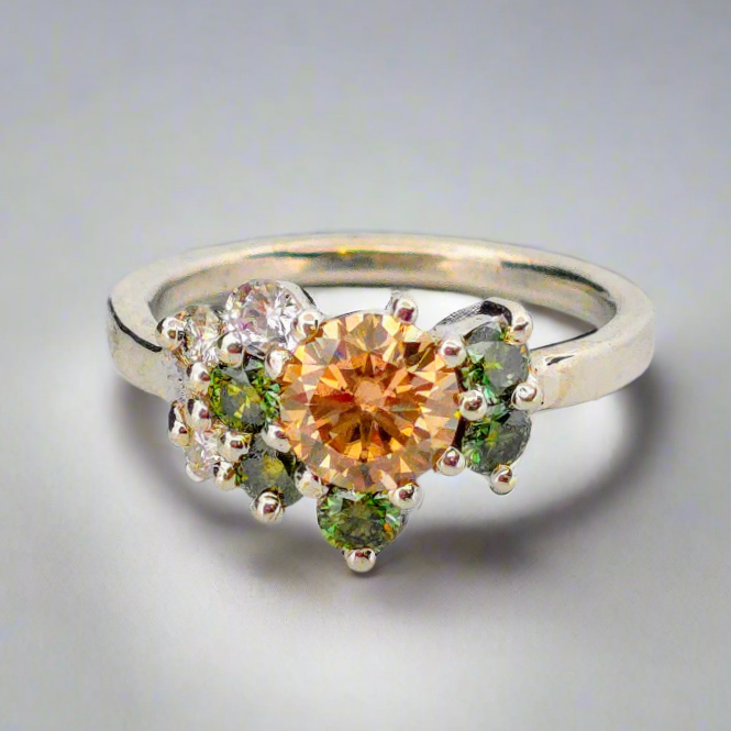 Silverring med orange och gröna moissaniter i elegant handgjord design mot neutral bakgrund.