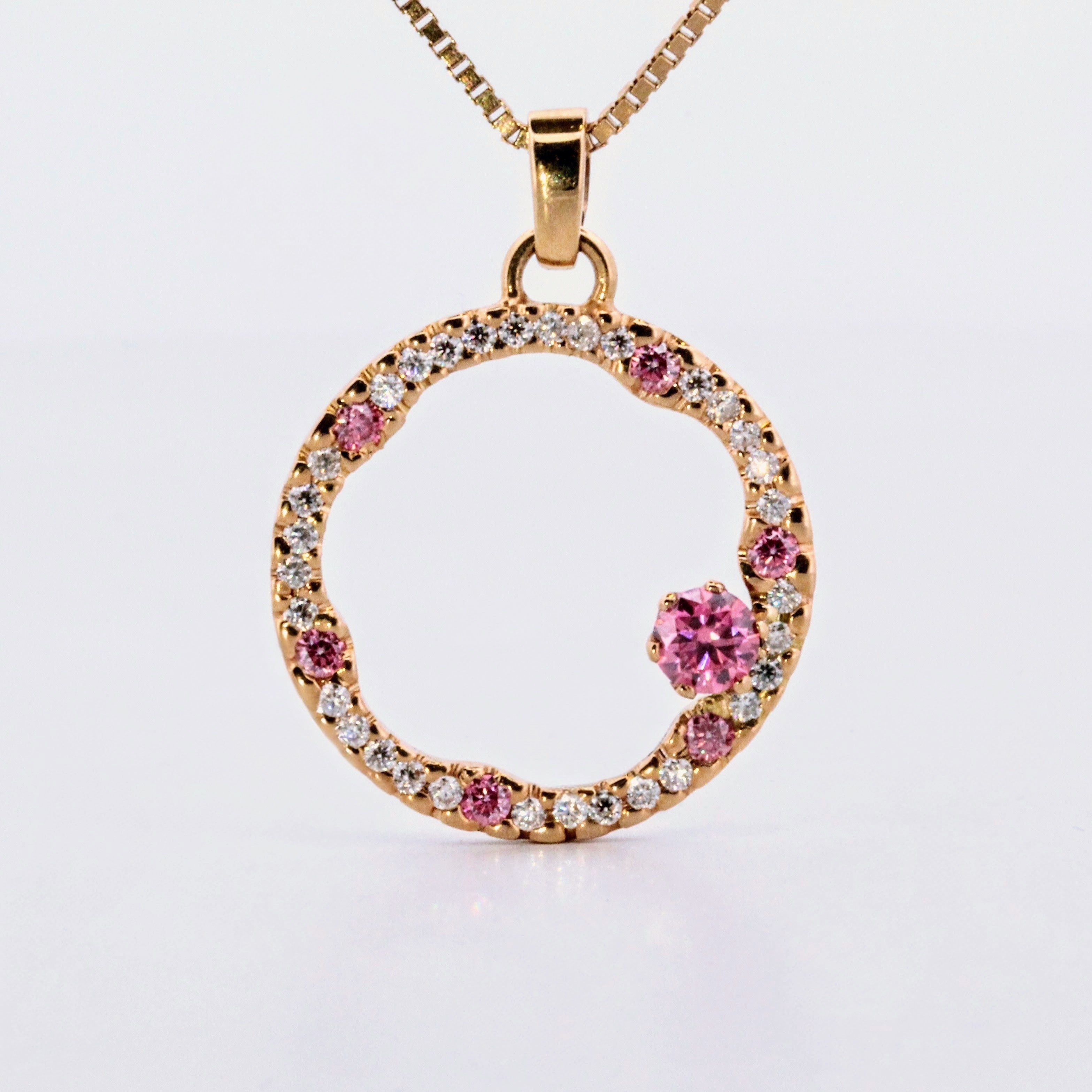 Hänge i 18k rödguld med en cirkelform prydd med vita och rosa moissaniter 