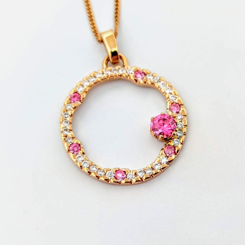 Hänge i 18k rödguld med en cirkelform prydd med vita och rosa moissaniter 