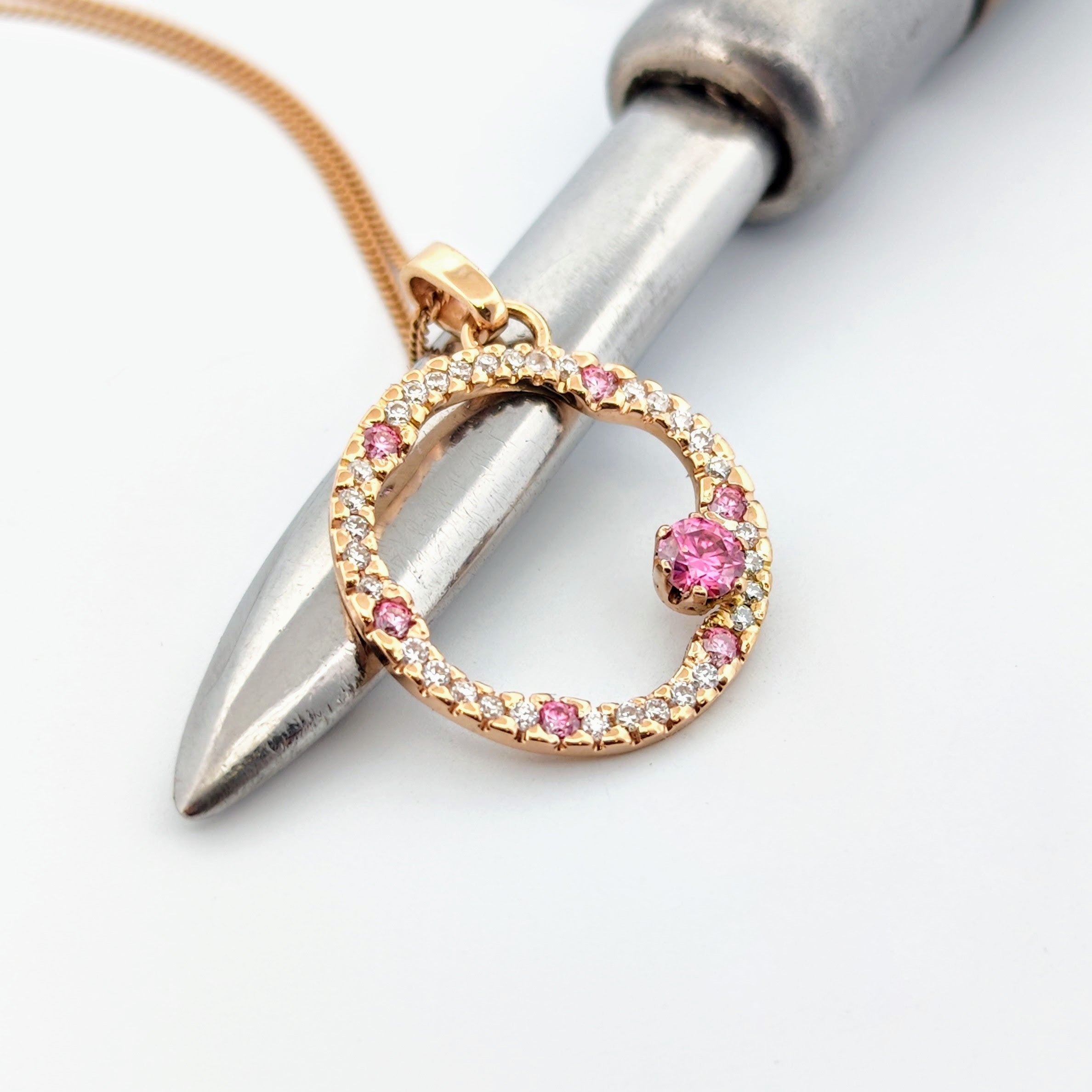 Hänge i 18k rödguld med en cirkelform prydd med vita och rosa moissaniter 