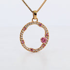 Hänge i 18k rödguld med en cirkelform prydd med vita och rosa moissaniter 